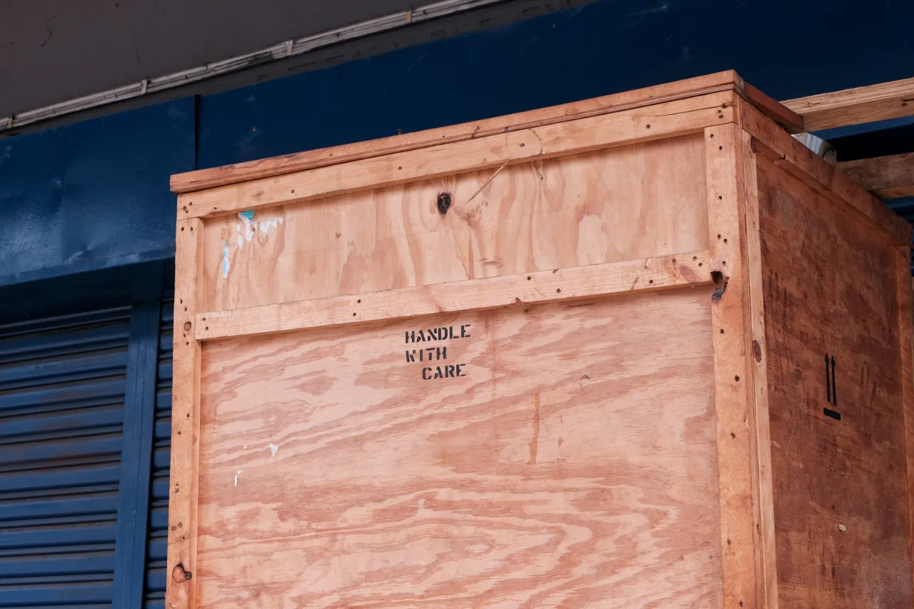 A large wooden box featuring a stamped sign that reads "handle with care."